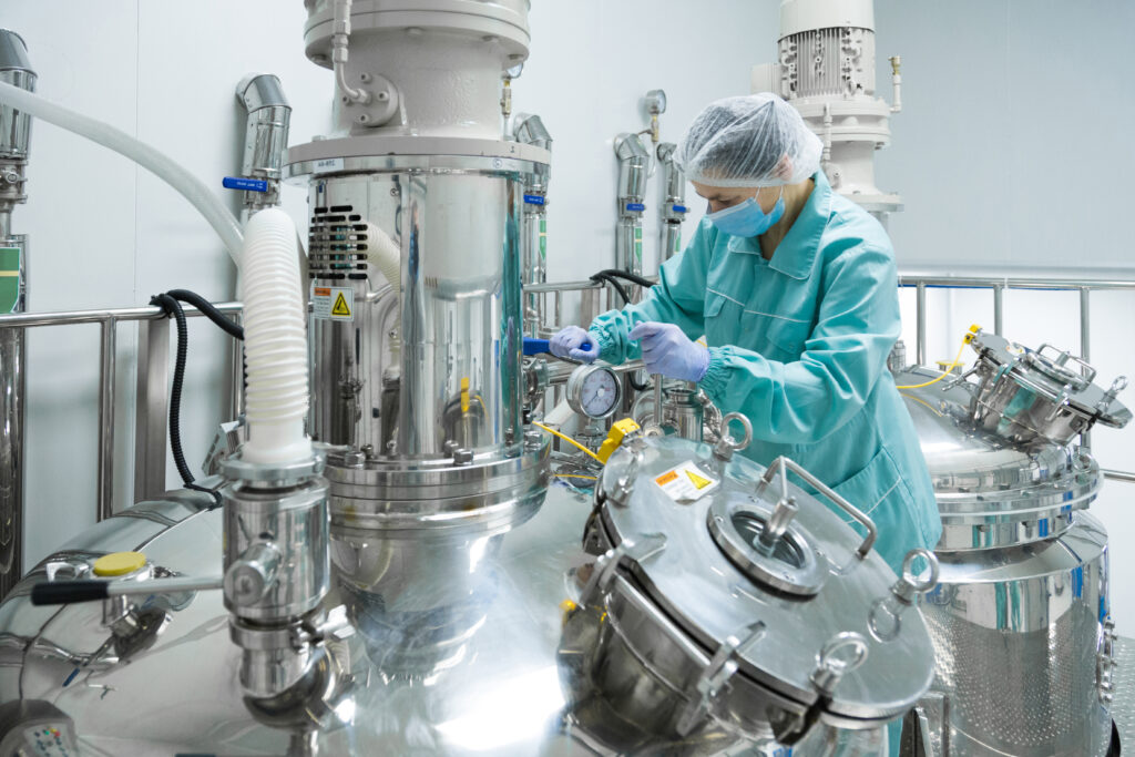 Home pharmaceutical factory woman worker in protective clothing operating production line in sterile environment
